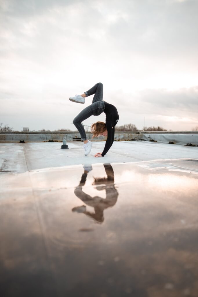 woman doing bridge posts reflecting on water puddle